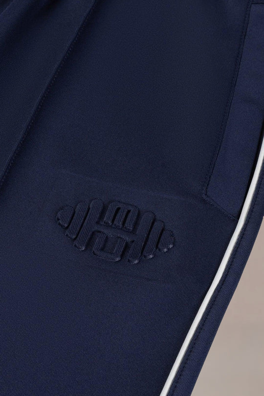 Detailshot van embossed halterlogo op blauwe heren sportbroek, close-up van hoogwaardig materiaal en textuur