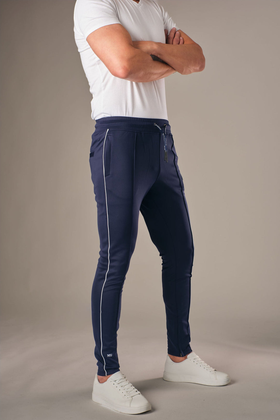 Blauwe muscle fit sportbroek voor heren met witte zijstreep en embossed halterlogo, full body vooraanzicht, gedragen met wit T-shirt en witte sneakers