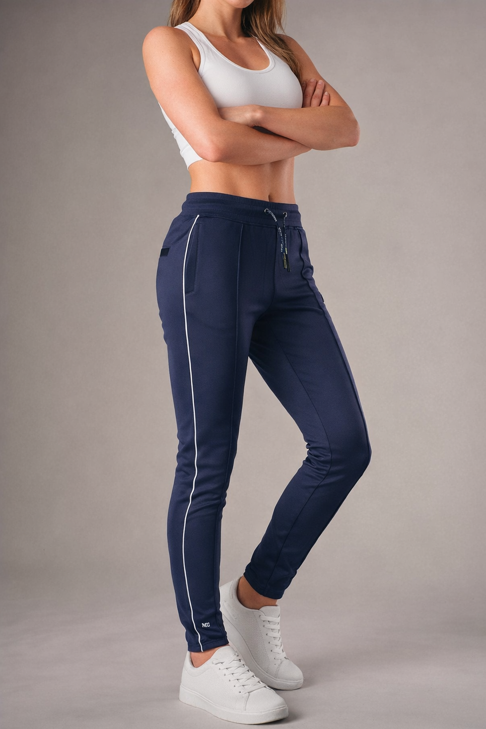blauwe muscle fit sportbroek voor dames met witte zijstreep en embossed halterlogo, full body vooraanzicht, gedragen met wit T-shirt en witte sneakers-