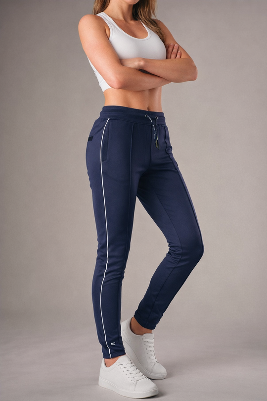 blauwe muscle fit sportbroek voor dames met witte zijstreep en embossed halterlogo, full body vooraanzicht, gedragen met wit T-shirt en witte sneakers-