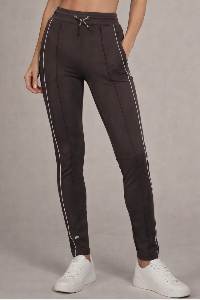 Grijze muscle fit sportbroek voor dames met witte zijstreep en embossed halterlogo, full body vooraanzicht, gedragen met wit T-shirt en witte sneakers.
