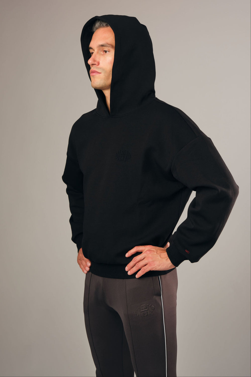 Model draagt Hoodie Z2 – luxe zwarte oversized en cropped herenhoodie met embossed logo, stijlvolle pasvorm en casual uitstraling
