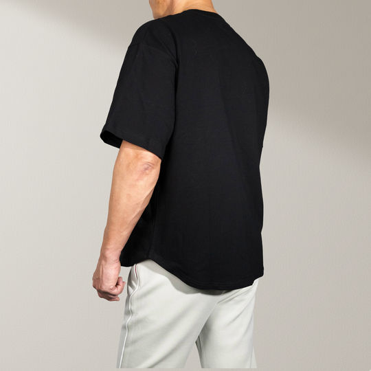 Achteraanzicht van zwarte oversized T-shirt voor heren van Muscle Up Store met minimalistische look, verlaagde schouders en premium zwaar katoen.