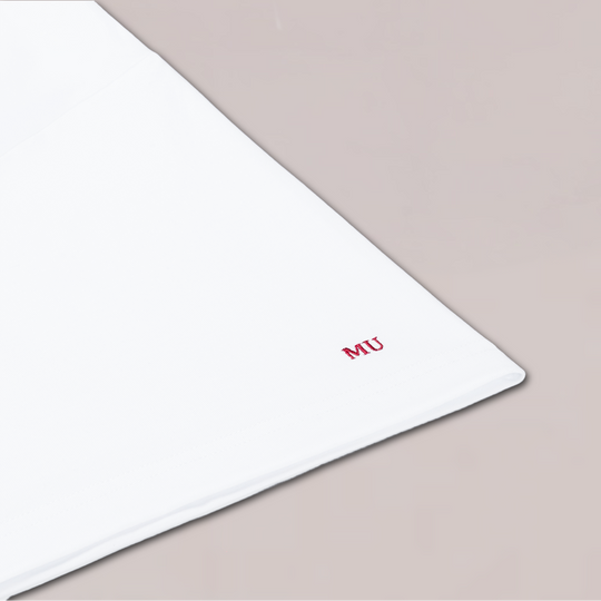 Close-up van witte T-shirt mouw van Muscle Up Store met rood MU-logo geborduurd, minimalistisch en premium afgewerkt.