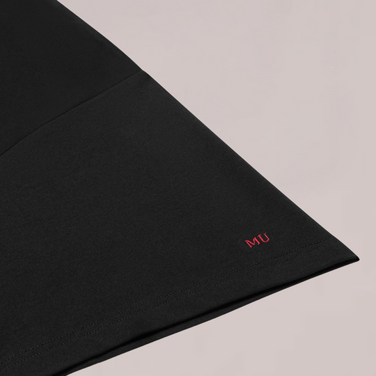Close-up van zwarte T-shirt mouw van Muscle Up Store met rood MU-logo geborduurd, minimalistisch en premium afgewerkt.